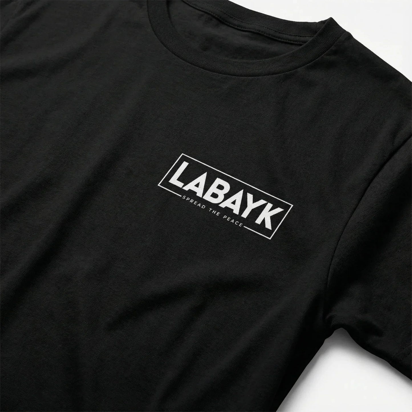 Close-up of black t-shirt with bold white LABAYK logo and 'Spread the Peace' text