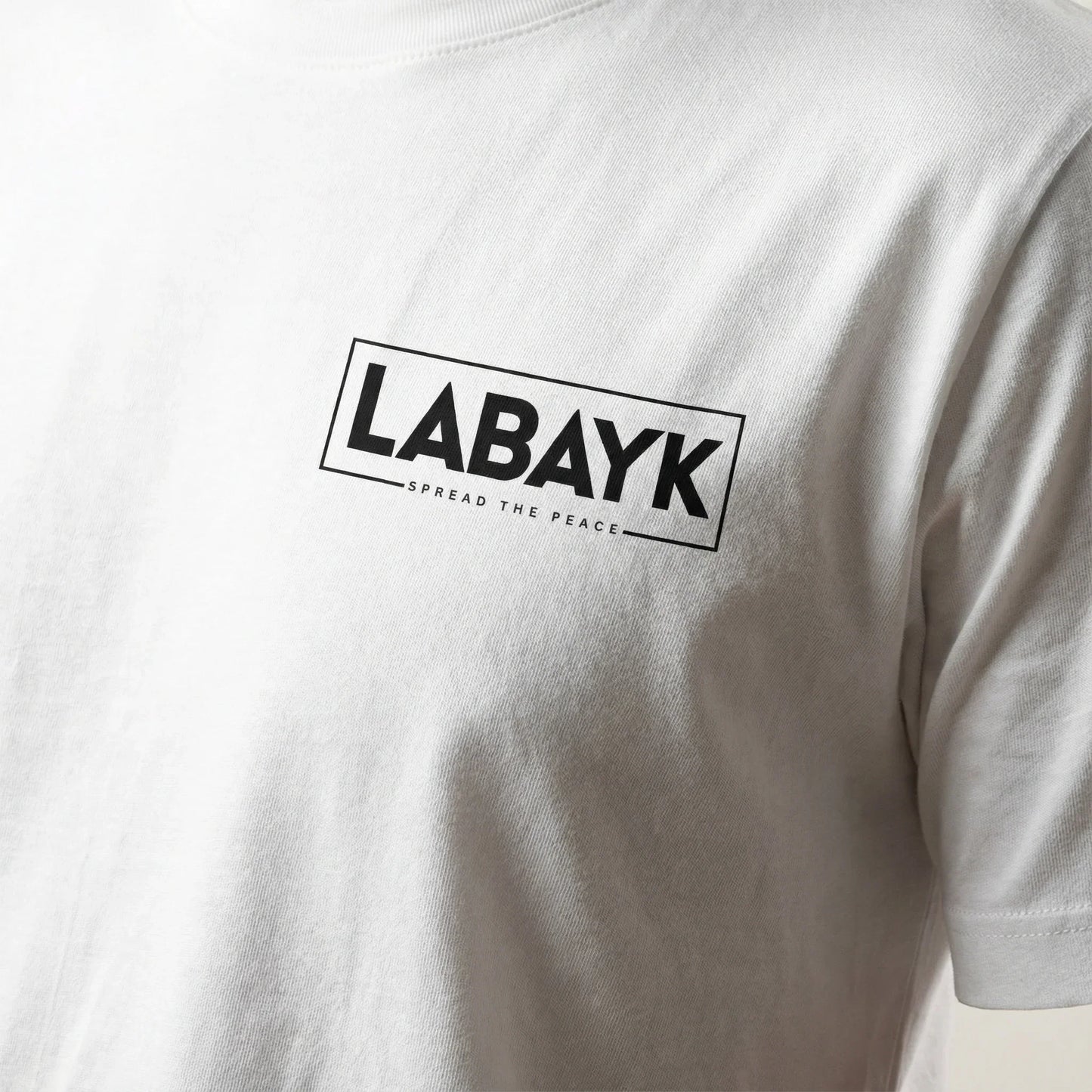 Close-up of white t-shirt with black LABAYK Spread The Peace logo on chest